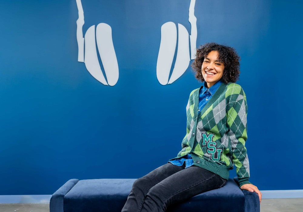 Model wearing Michigan State argyle cardigan with msu chenille interlock patch