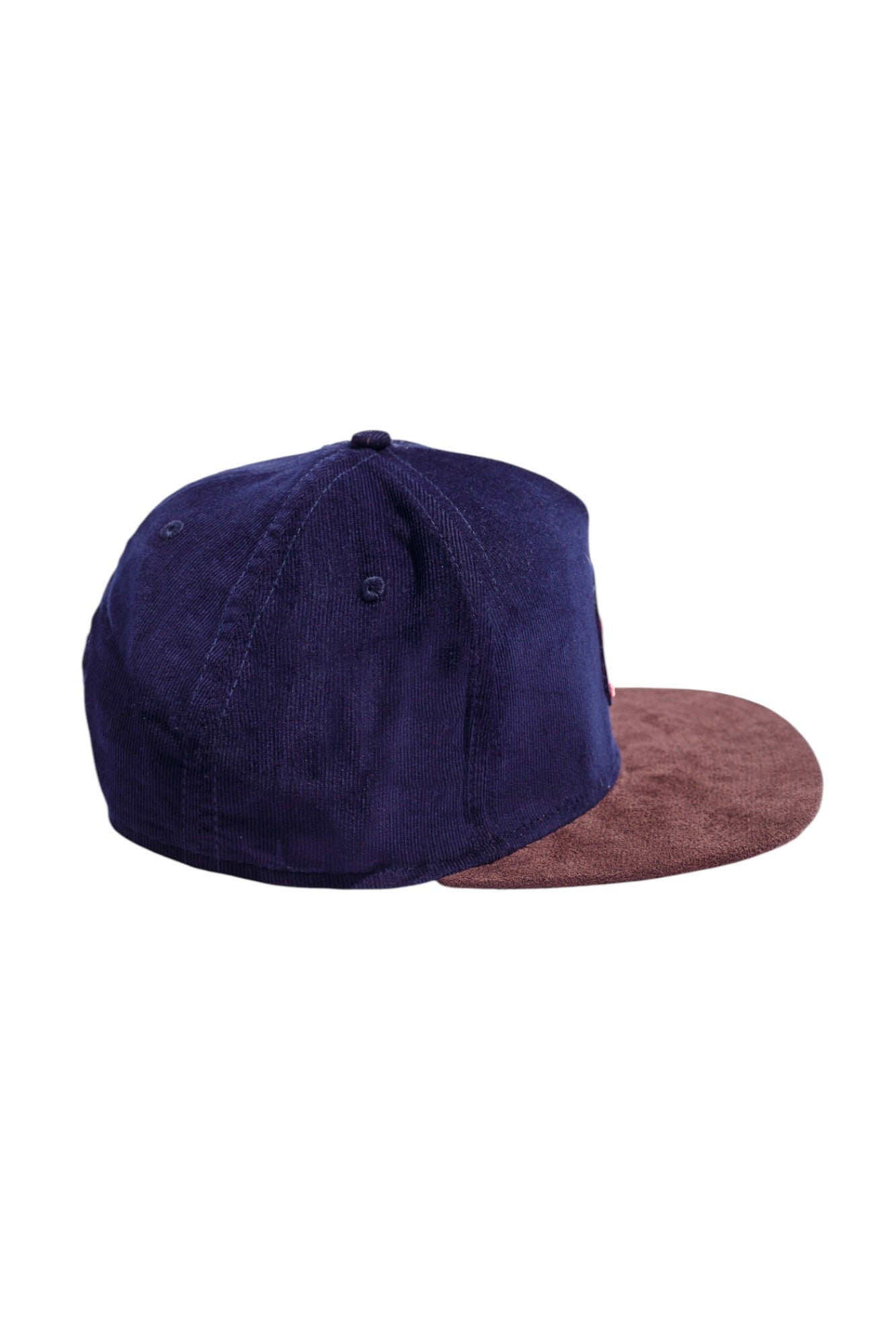 Side profile of navy and brown high-crown snapback hat highlighting suede and corduroy texture.