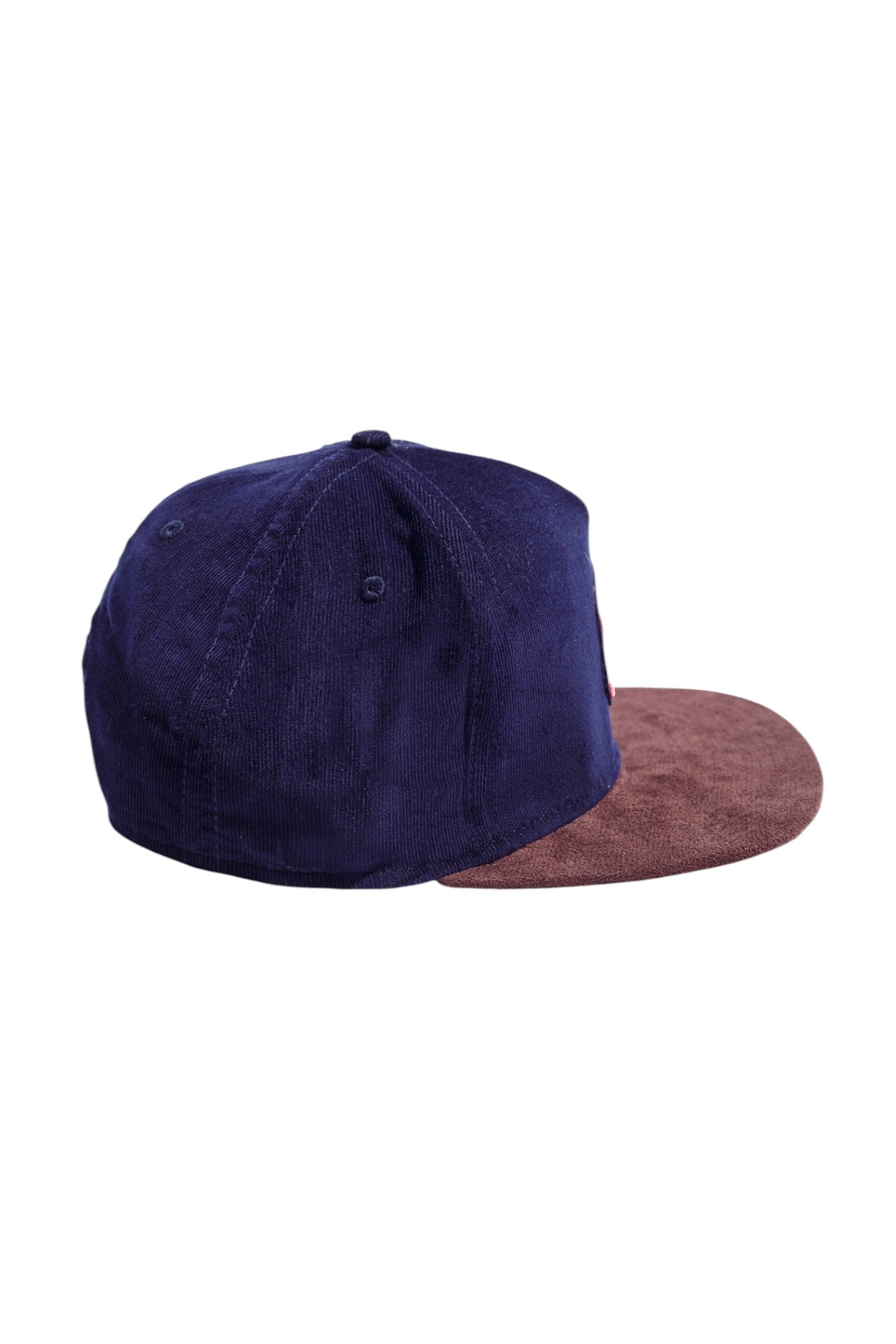 Side profile of navy and brown high-crown snapback hat highlighting suede and corduroy texture.
