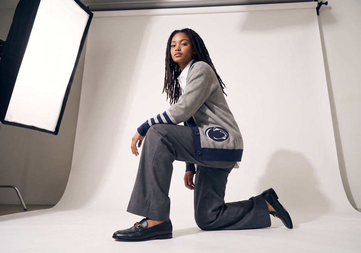 Female model wearing Penn State University letterman band cardigan with Nittany Lion embroidered applique varsity patch sewn onto lower front side.