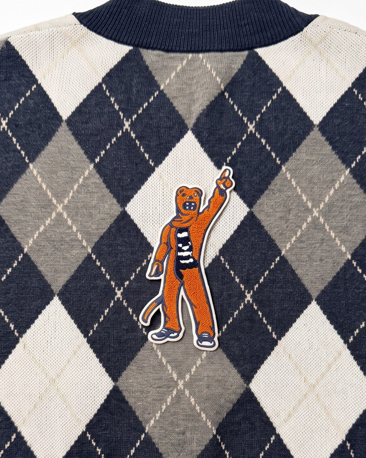 Penn State Nittany Lion mascot chenille varsity patch in brown, navy and white sewn onto back of navy, grey, and white argyle knit sweater.