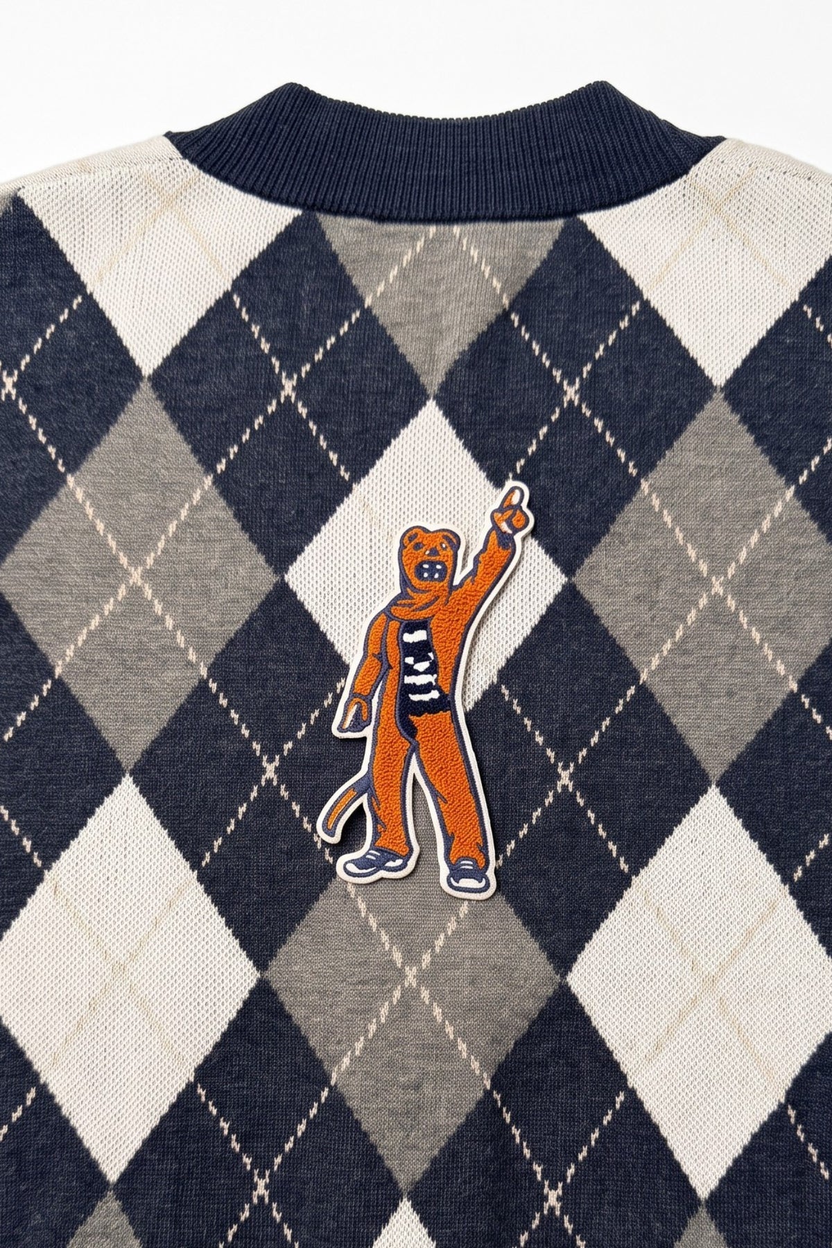 Penn State Nittany Lion mascot chenille varsity patch in brown, navy and white sewn onto back of navy, grey, and white argyle knit sweater.
