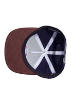 Underneath view of navy corduroy and brown suede snapback hat showing the undervisor and interior construction.