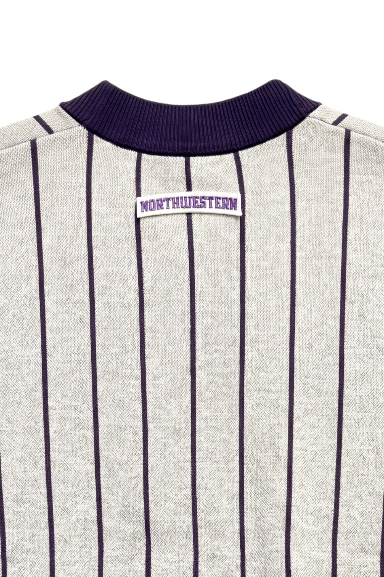 Close up of light grey and purple Northwestern University heritage pinstripe cardigan knit sweater with arched white crest patch with NORTHWESTERN embroidered in purple sewn onto the upper center back below the collar.