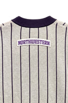 Close up of light grey and purple Northwestern University heritage pinstripe classic crewneck knit sweater with arched white varsity patch with NORTHWESTERN embroidered in purple sewn onto the upper center back below the collar.
