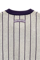 Close up of light grey and purple Northwestern University heritage pinstripe classic crewneck knit sweater with arched purple crest patch with NORTHWESTERN embroidered in white sewn onto the upper center back below the collar.