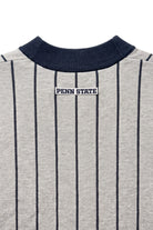 Penn State University block letter embroidered iron-on crest patch in navy and white sewn onto upper back below collar of light grey and navy pinstripe classic crewneck knit sweater