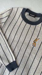 Penn State Nittany Lion mascot embroidered crest patch in brown, navy and white sewn onto left chest of light grey classic crewneck knit sweater with navy pinstripes and trim. 